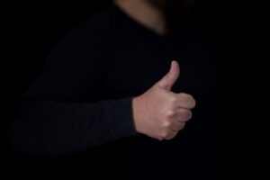 Decorative image of a white person's hand making a thumbs up gesture against a dark background